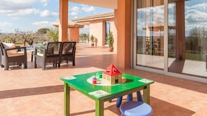 An outdoor patio with a table and chairs, a children's play table, and a view of the sky and trees.