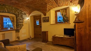 A cozy living room with a stone wall, wooden furniture, a television, and a Christmas tree.