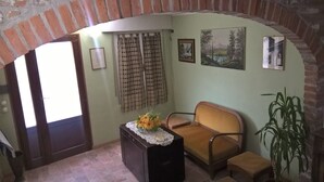 A cozy room with a brick archway, a sofa, a small table with a flower arrangement, and a potted plant.