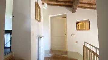 Una scala con gradini in legno che conduce a un pianerottolo, una porta bianca e una piccola finestra.