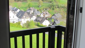 Un balcon donnant sur un quartier résidentiel, avec des maisons et un champ verdoyant.
