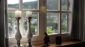 Une fenêtre ornée de deux chandeliers blancs et d’une petite figurine posée sur le rebord.