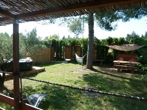 Ein Garten mit einer Holz-Pergola, einer Hängematte, einem Whirlpool und einem Picknicktisch.