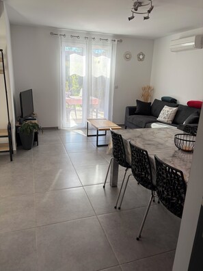 A modern living room with a sofa, a dining table, and a TV.