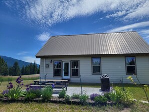 A single-story house with a metal roof, a front door, and a small porch. - Epic Views - Peaceful, Eco-friendly Home - 30 Minutes to Glacier National Park (Kalispell)