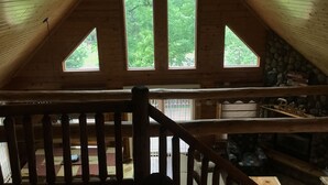 A wooden cabin with a sloped ceiling, large windows, and a stone wall. - Hana Log Cabin near Devil's Lake (Baraboo)