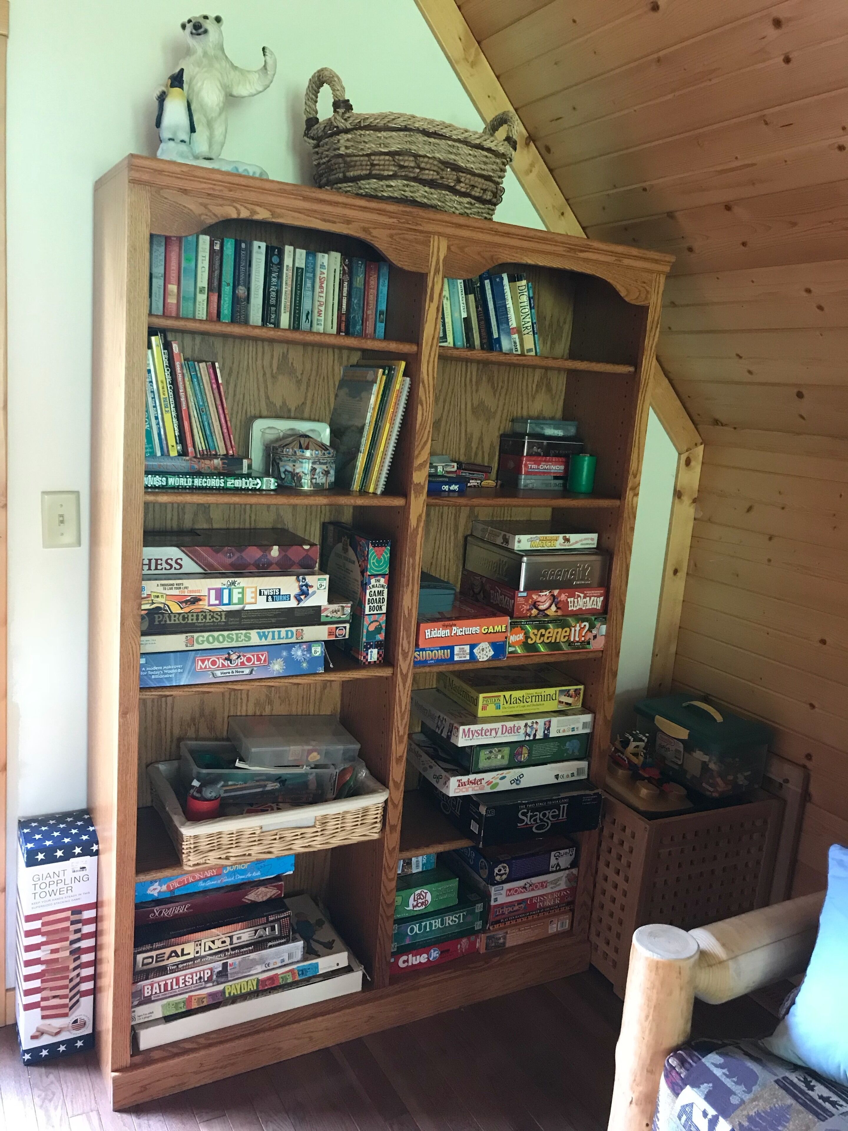 Une bibliothèque en bois remplie de divers jeux de société et de livres.