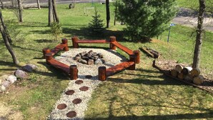 A circular wooden fire pit surrounded by pebbles and logs, with a gravel path leading to it. - Hana Log Cabin near Devil's Lake (Baraboo)