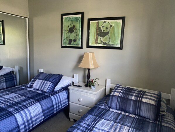Habitación de hotel con dos camas, una mesita de noche, una lámpara y dos obras de arte enmarcadas en la pared.