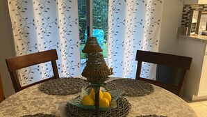 A dining table with a woven centerpiece, a glass bowl of lemons, and a patterned tablecloth.