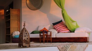 Ein gemütliches Wohnzimmer mit einem weißen Sofa, bunten Kissen, einem gewebten Korb und einem Holztisch.