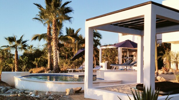 Ein moderner Außenpoolbereich mit Liegestühlen und einer Pergola.