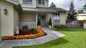 A two-story house with a front porch, a small garden with marigolds, and a wooden fence. - Peak View Retreat, 3 Bedroom Sleeps 6 (Flagstaff)