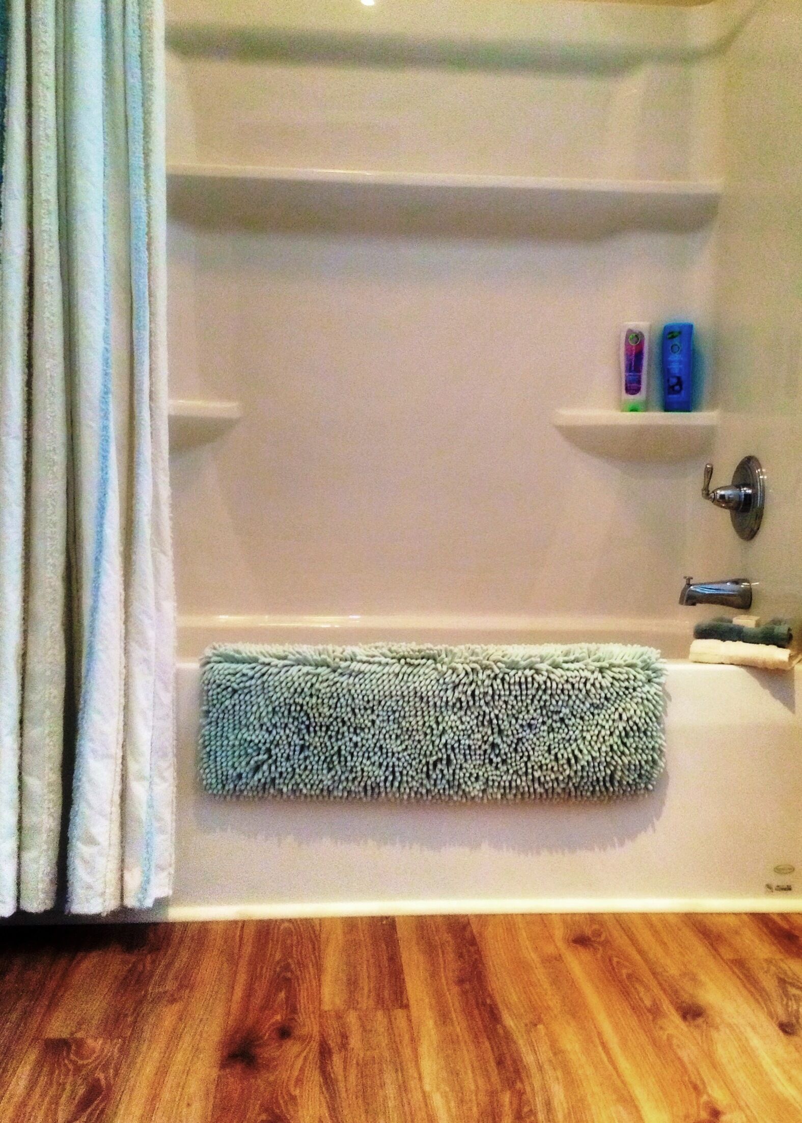 Een badkamer met een bad, een handdoekhouder met een handdoek, en een plank met toiletartikelen.