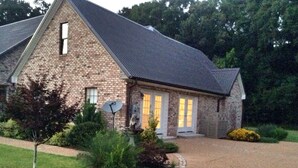 Una casa de piedra con techo inclinado, una antena parabólica y un jardín bien cuidado.