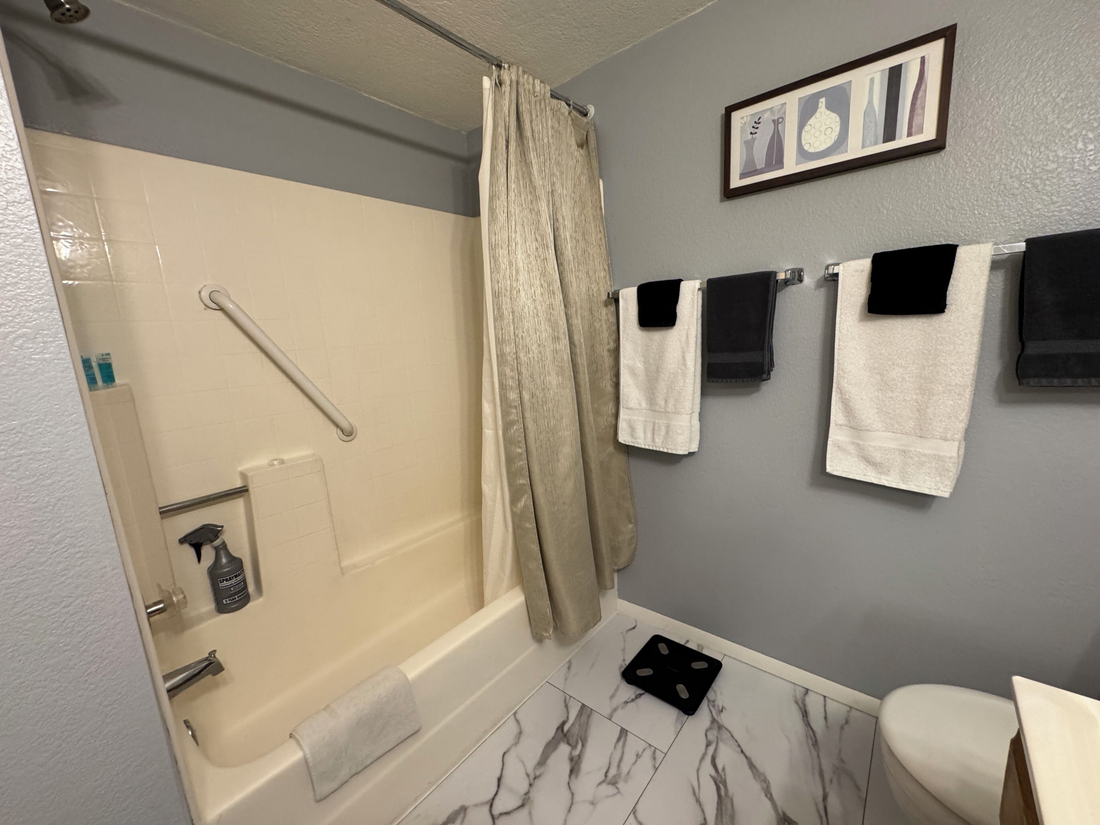 Un baño con ducha, inodoro, bañera y un perchero con varias toallas.