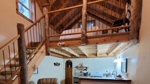 A loft-style living area with a wooden staircase, leather furniture, and a view of the kitchen. - A remote cabin surrounded by Pine, Birch and Aspen trees, five miles to Deadwood (Deadwood)