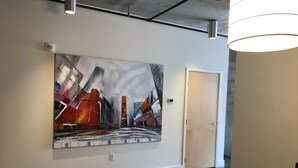 Modernin taiteen galleria, jonka seinällä on suuri abstrakti maalaus, ja jossa on puinen ovi sekä musta tuoli.