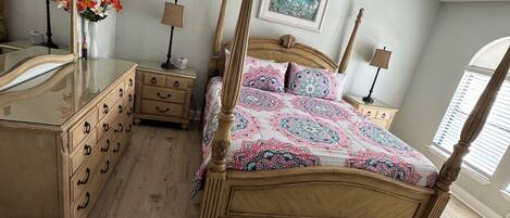 Une chambre à coucher avec un lit à baldaquin, une commode, une coiffeuse et une chaise.
