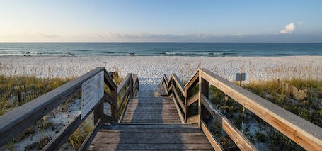 A wooden boardwalk leading to a beach with a clear view of the ocean.