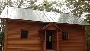 A log cabin with a metal roof, a front porch, and a small window. - Ultimate relaxing vacation  (Orwell)