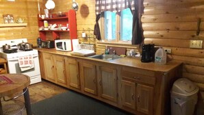 A compact kitchen with wooden cabinets, a microwave, a sink, and a stove. - Ultimate relaxing vacation  (Orwell)
