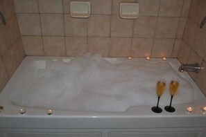 Relax in a spacious bathtub surrounded by a tiled wall.