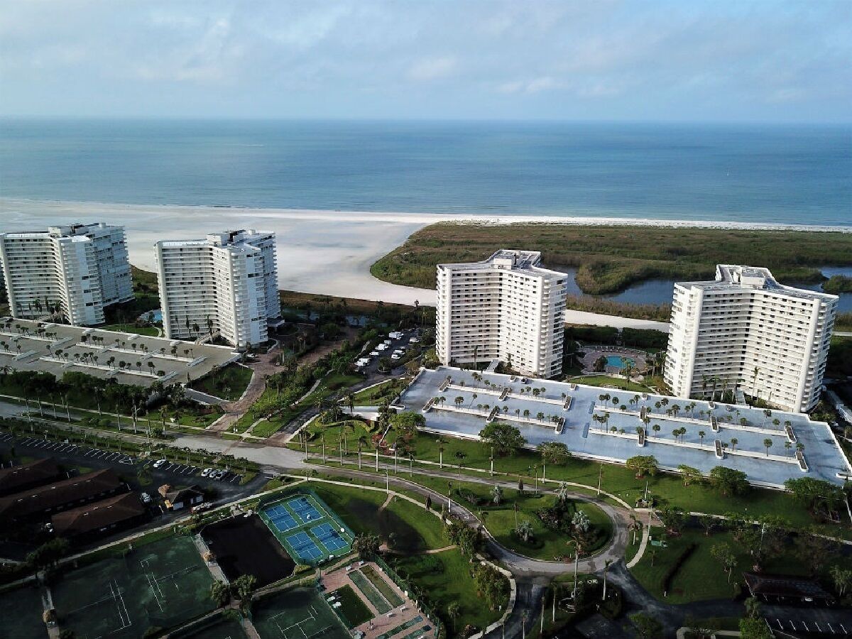 A high-rise hotel complex with multiple buildings, a central courtyard, and a view of the beach and ocean.