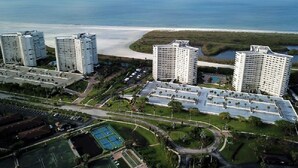 A high-rise hotel complex with multiple buildings, a central courtyard, and a view of the beach and ocean. - Marco Island Remodeled Condo, SSNW, T4, 1408 2 Bd, 2 Ba, SPECTACULAR Sunsets 365 (Marco Island)