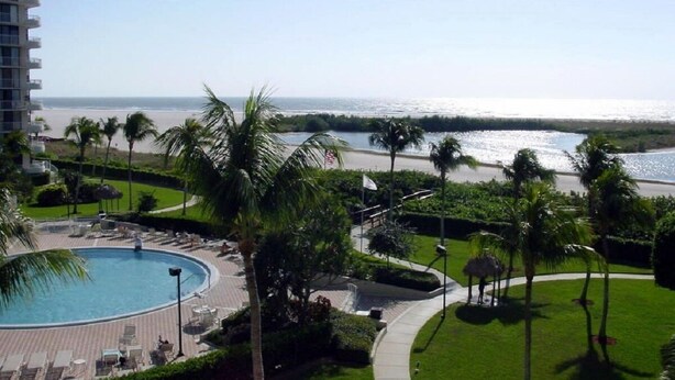 A hotel with a pool, palm trees, and a view of the ocean. - Marco Island Remodeled Condo, SSNW, T4, 1408 2 Bd, 2 Ba, SPECTACULAR Sunsets 365 (Marco Island)