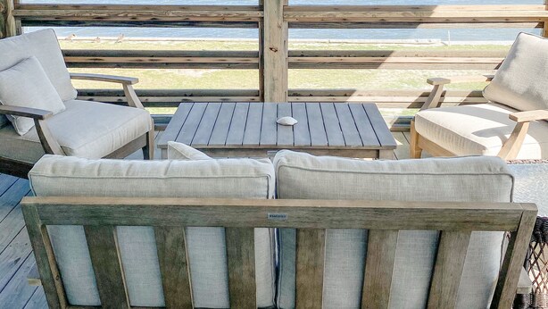 A wooden deck with a cushioned bench and a small table, overlooking a body of water. - Peaceful Getaway with Amazing Views - Cape Lookout & Beaufort nearby - SLEEPS 8 (Davis)