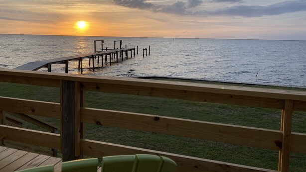 A wooden deck with a view of the ocean at sunset. - Peaceful Getaway with Amazing Views - Cape Lookout & Beaufort nearby - SLEEPS 8 (Davis)