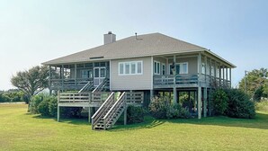 A two-story house with a covered porch and a staircase leading to the second floor. - Peaceful Getaway with Amazing Views - Cape Lookout & Beaufort nearby - SLEEPS 8 (Davis)