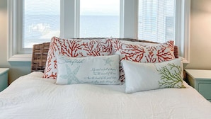 A bedroom with a large bed, three windows, and a view of the sea. - Peaceful Getaway with Amazing Views - Cape Lookout & Beaufort nearby - SLEEPS 8 (Davis)