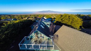 A house with a large deck, a view of the ocean, and a mountainous landscape in the background. - Haleakala Sunrise Home, Kula, Maui, Hawaii (Kula)