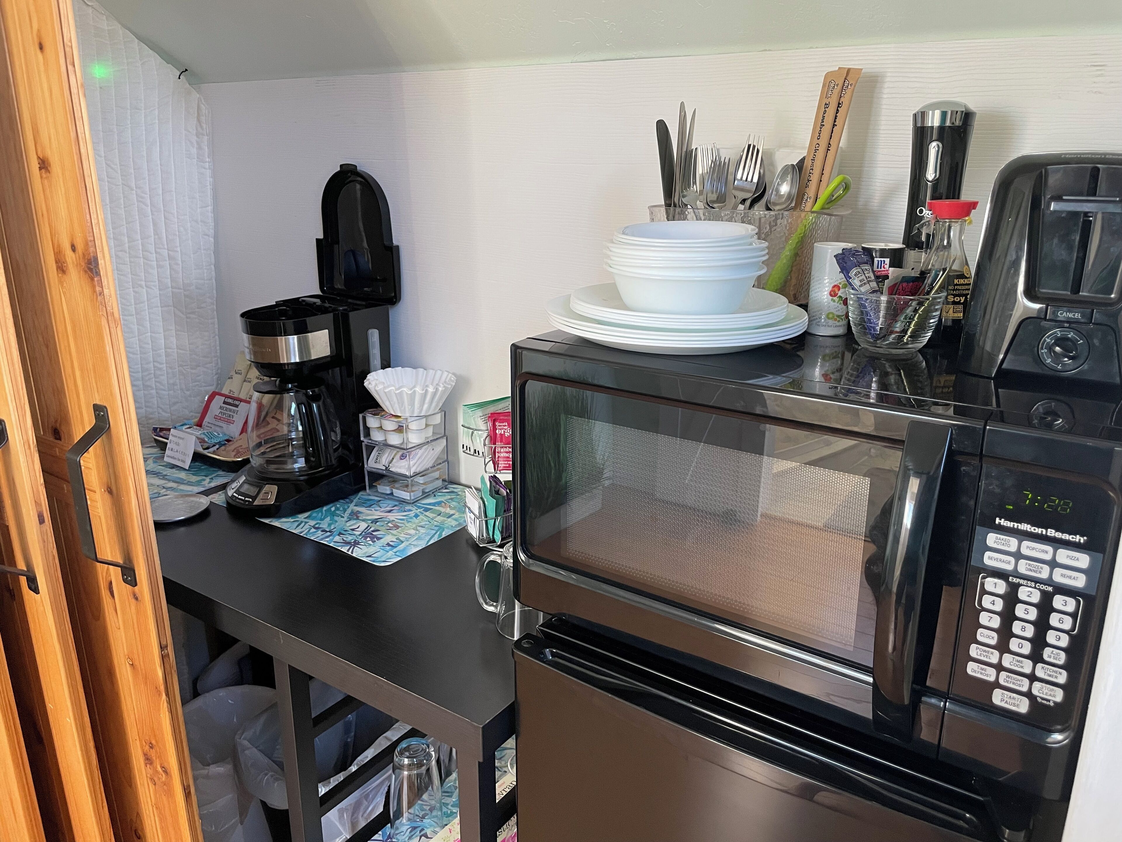 A compact kitchenette with a microwave, coffee maker, and a small refrigerator.
