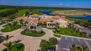 A large, multi-story building with a central courtyard, surrounded by palm trees and a parking lot. - Escape the coldest and snowiest winter in years by "Springing" into Treviso Bay! (Naples)