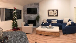 A living room with a fireplace, a blue sofa, a Christmas tree, and a flat-screen TV. - Enjoy the beach life! Walk to beach and pier+Roof Deck& Garage in Hermosa Beach (Hermosa Beach)