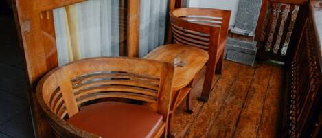 A wooden chair with a cushioned seat and backrest, positioned next to a wooden table.