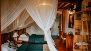 Une chambre avec un lit sous un dais, une chaise en bois, une petite table avec une lampe et une chaise en osier.