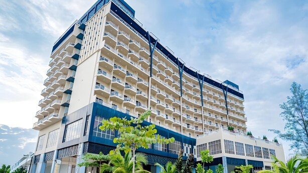 A multi-story hotel with a modern design, featuring balconies on each floor, surrounded by lush greenery. - Amerald Resort Hotel (Pengerang)
