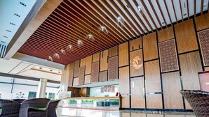 A modern hotel lobby with a wooden ceiling, patterned wall panels, and a reception desk. - Amerald Resort Hotel (Pengerang)