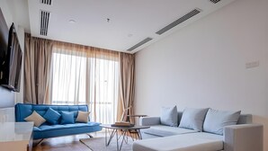 A modern living room with a blue sofa, a grey sectional, and a small table. - Amerald Resort Hotel (Pengerang)