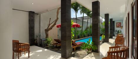A modern indoor pool area with wooden lounge chairs, a pool, and potted plants.