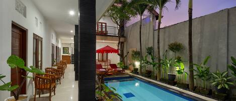 Zona de piscina con mobiliario para comer y plantas en macetas.