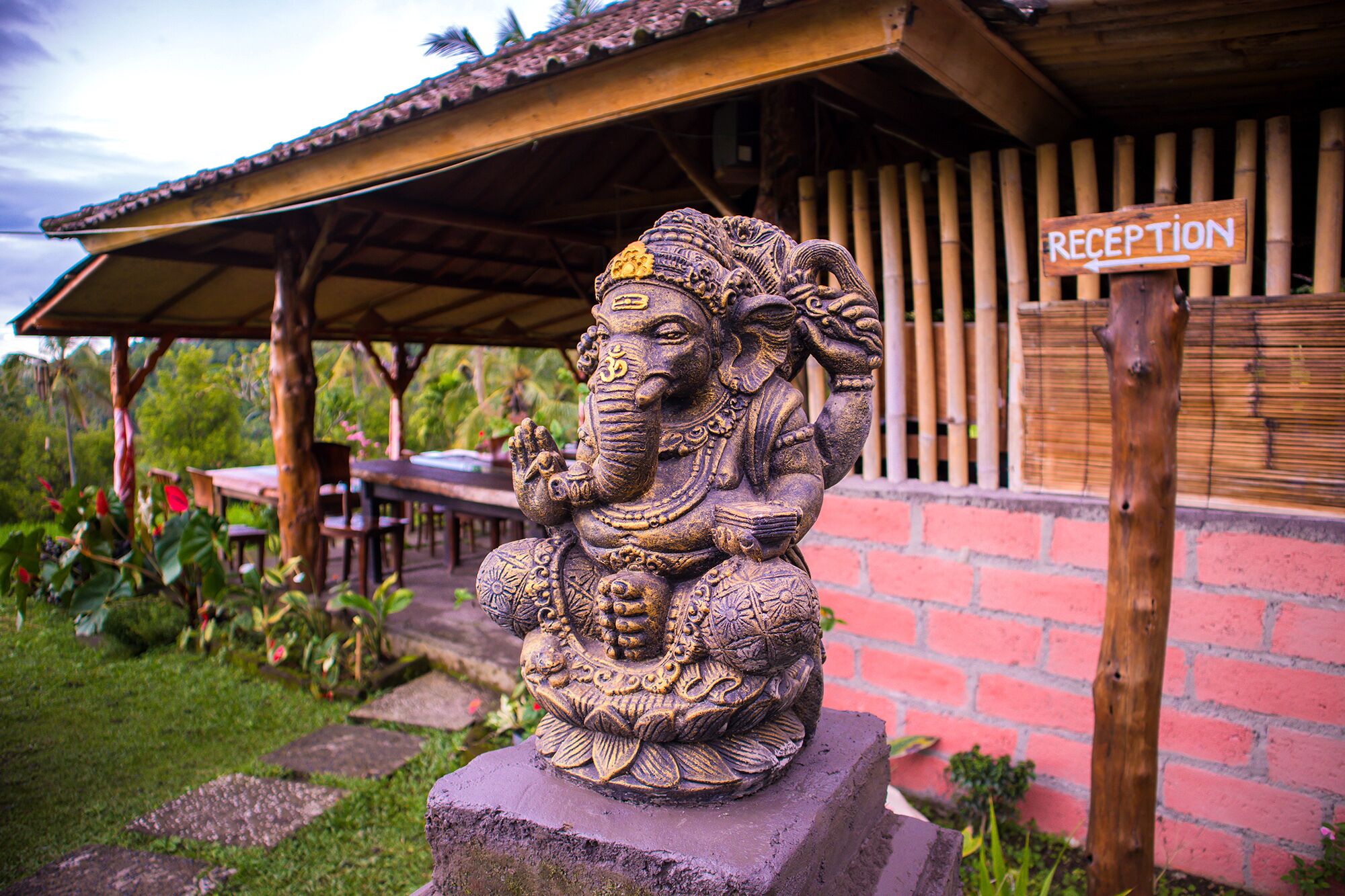 A reception sign and a detailed elephant statue in front of a building with a tiled roof and a brick wall.