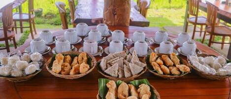 A round wooden table with white teacups and various food items in baskets.
