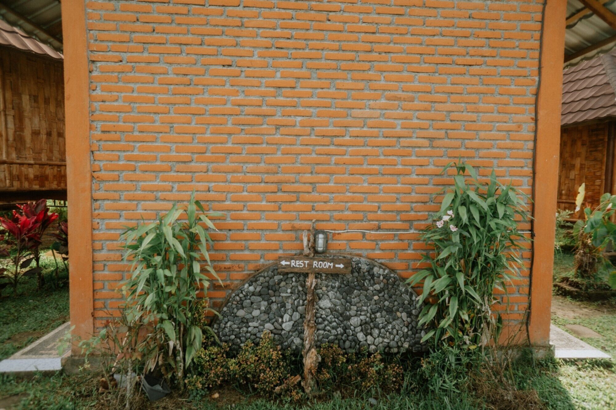 Pared de ladrillo con un letrero que indica un baño.