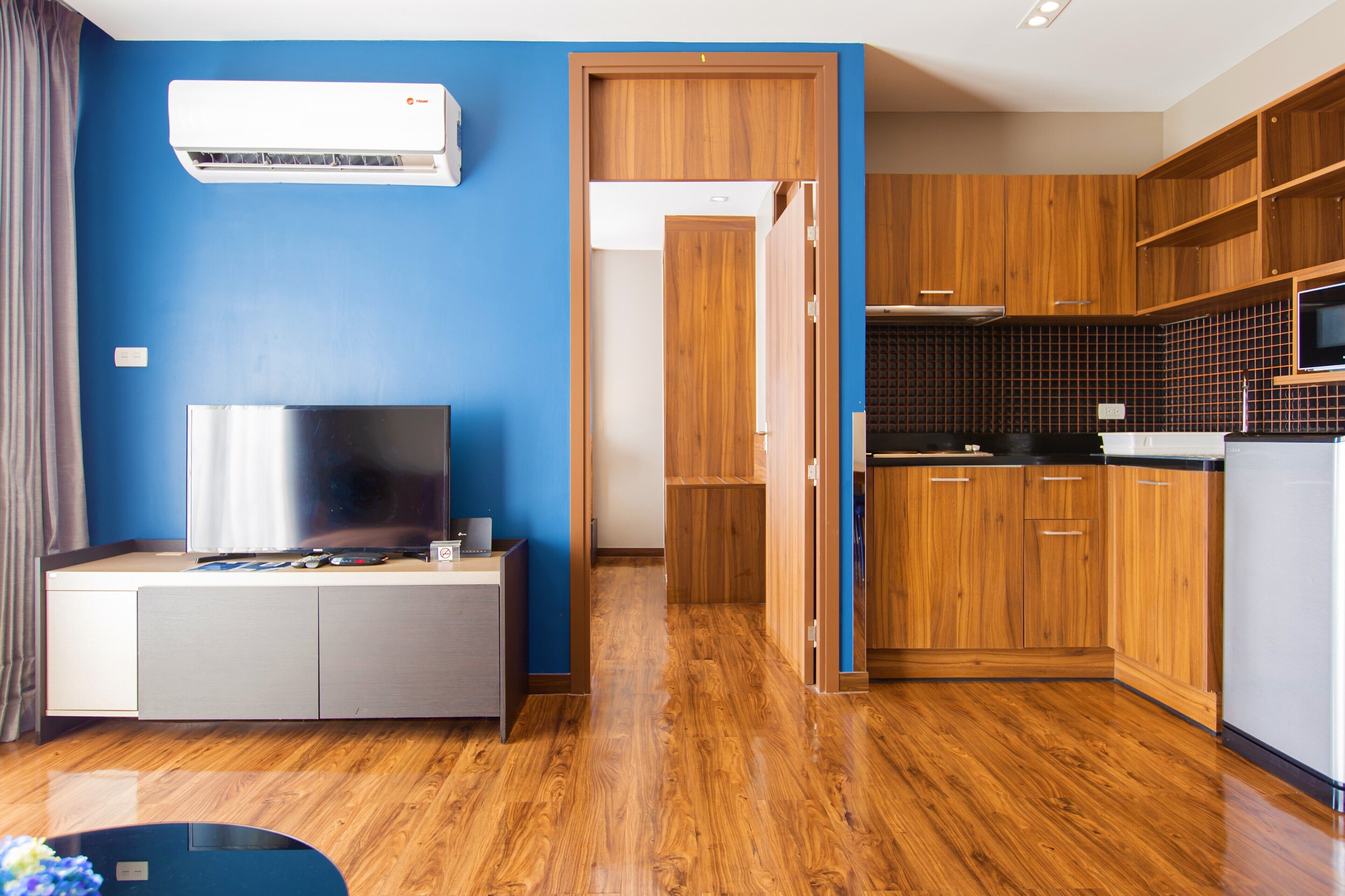 Een moderne woonkamer met een flatscreen televisie, een klein tafeltje en een blauwe muur.