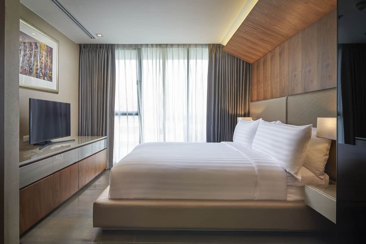 A modern hotel room with a large bed, a flat-screen TV, and a painting on the wall.
